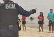 Descumprindo interdição, grupo de banhistas é orientado a sair da praia da Ponta Negra na extrema vazante do rio
